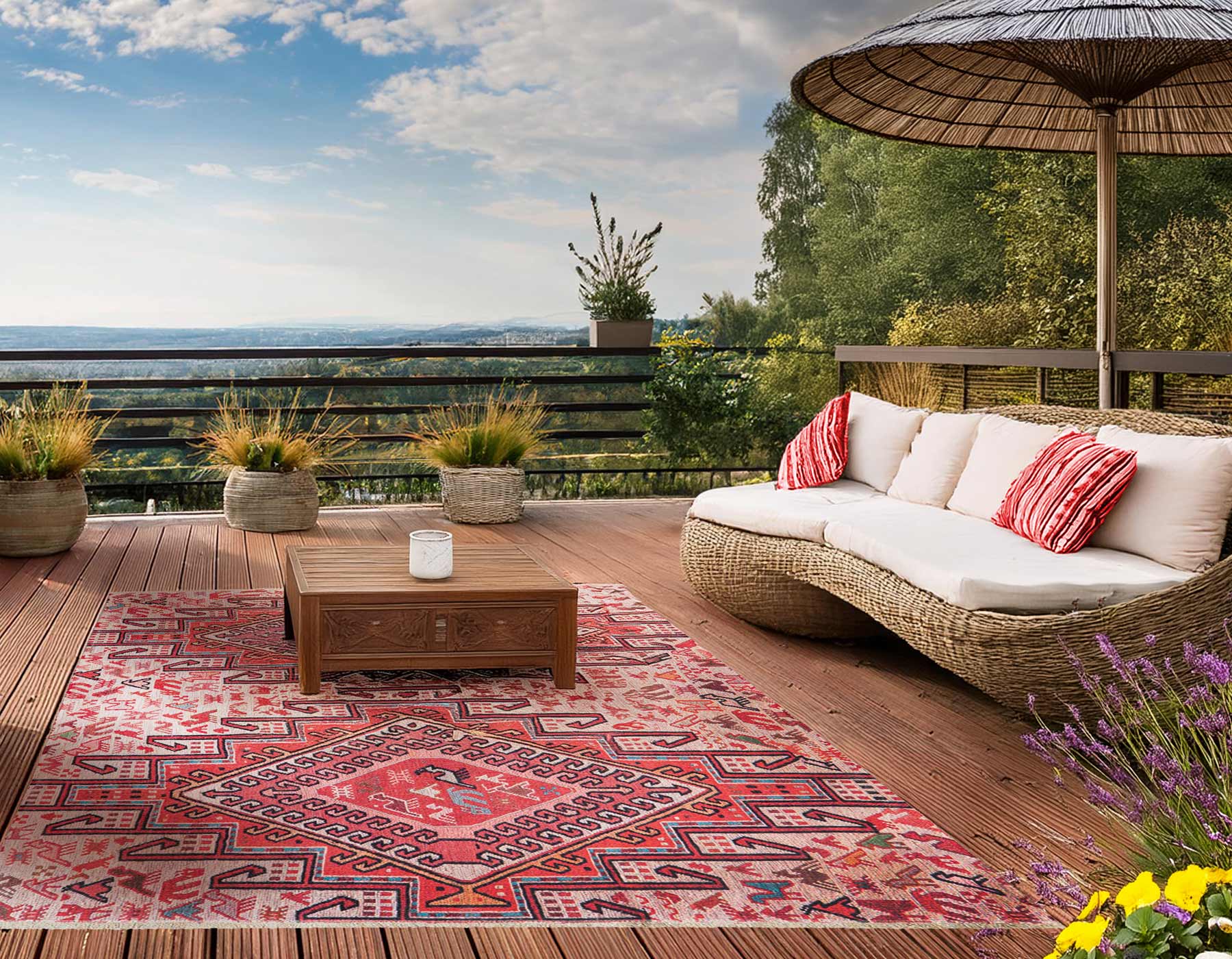 Große Terasse mit Blick in ein Tal. Mit Rattanmöbel und Sonnenschirm. Auf der Terasse liegt ein großer roter Outdoor-Teppich im Ethno Look.
